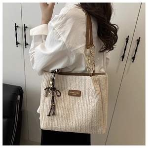 Detail of woven tote bag with brown leather straps and gold chain link accents