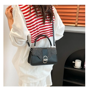 Detail of elegant black glitter crossbody bag with silver buckle and round handle