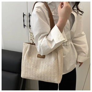 Close-up of woven tote bag with V-shaped texture, brown leather straps and metal chain