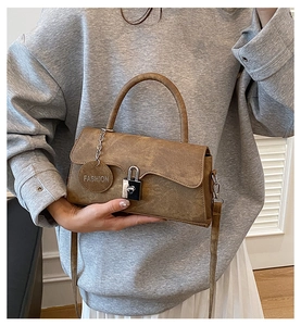 Detailansicht der braunen Ledertasche mit silbernem Schloss und dekorativem Anhänger