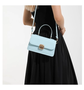 Model wearing a structured light blue leather handbag with elegant gold square metal lock