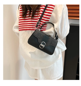 Detail of black glitter handbag with silver ring buckle shown on a female model