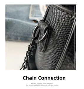 Détail de la texture cuir Saffiano noir et du maillon de chaîne en métal sur un sac