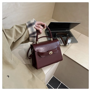 Close-up of a dark red vintage handbag with a gold metal twist lock in an office setting