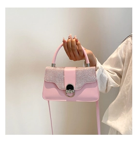 Detailed view of pink leather handbag featuring a glitter flap and metal ring twist lock