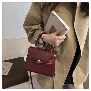 Dettaglio della borsa a mano in pelle opaca bordeaux con chiusura a rotazione