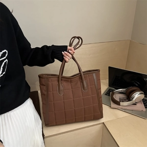 Deep brown quilted tote bag with square stitching and leather handles for autumn fashion