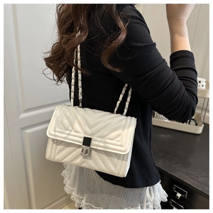 Close-up of a white quilted crossbody bag with silver lock and metal chain strap