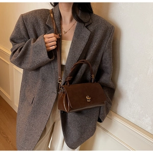Close-up of retro brown suede tote bag featuring a metallic twist lock and smooth texture