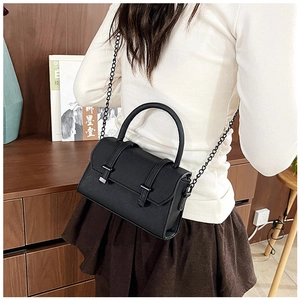 Détails d'un sac bandoulière noir mat avec deux sangles décoratives à boucle rétro