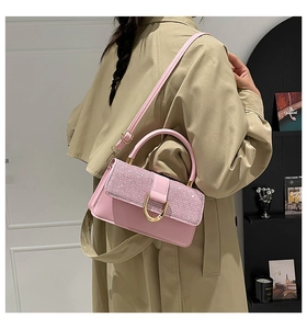 Detail of pink sequin shoulder bag with golden horseshoe buckle and leather strap