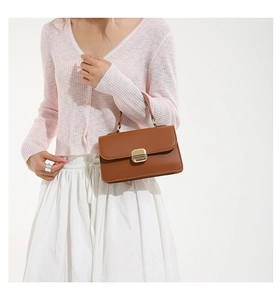 Close-up of brown leather handbag with gold metal twist lock held by model