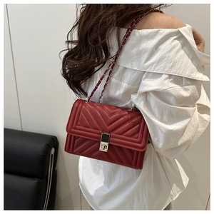 Detail view of red quilted shoulder bag with silver chain strap and metal clasp closure