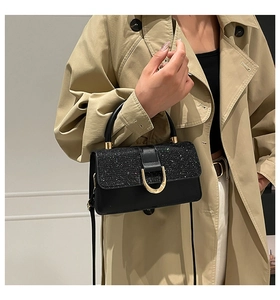 Detail of black sequin patchwork and gold U-shaped buckle on a luxury crossbody bag