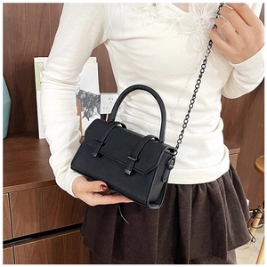Gros plan du sac bandoulière en cuir noir avec chaîne en métal et sangles à boucles décoratives