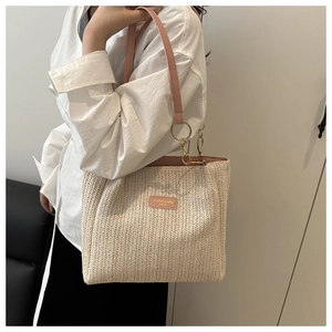 Detail of pink leather handles and woven texture on a cream straw tote bag