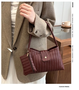 Detailed macro view of deep red woven leather texture and metal buckle on shoulder bag