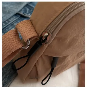 Detail shot of khaki nylon handbag featuring smooth silver metal zipper and woven strap
