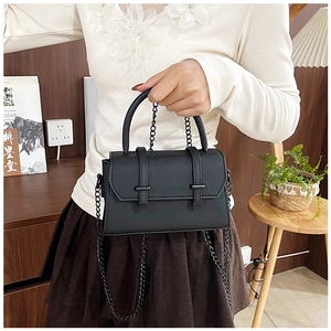 Détail d'un sac bandoulière noir avec texture croisée et bandoulière en chaîne