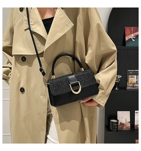 Detail of a chic black crossbody bag featuring a sequin flap and gold U-shaped lock buckle