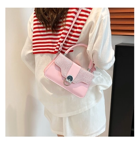 Pink crossbody bag with glitter flap and silver ring buckle worn by a model in interior