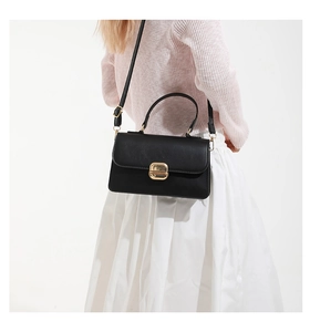 Classic black leather crossbody bag with gold buckle worn with pink knit top and white skirt