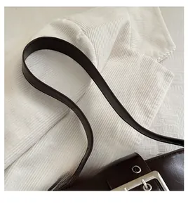 Detail of dark brown leather shoulder bag with silver hardware and precise stitching