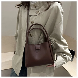 Detail of dark brown leather bucket bag showing the double top handles and soft texture