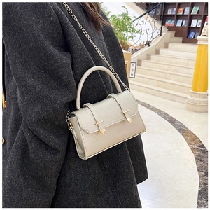 Détail d'un sac à main en cuir beige clair avec boucles dorées et bandoulière