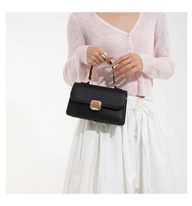 Detail view of the black matte leather small square bag featuring a gold rectangular lock