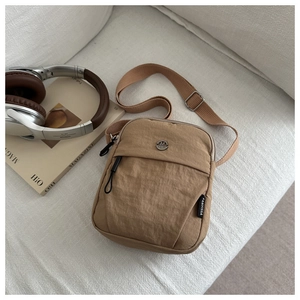 Minimalist khaki nylon crossbody bag with adjustable wide strap and metallic logo