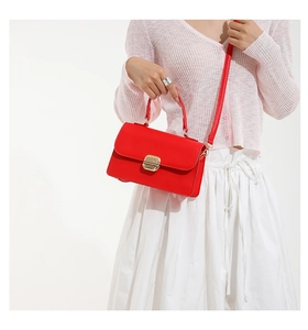 Close-up of a red leather crossbody bag featuring an elegant gold metal square buckle