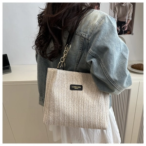 Detail of woven tote bag featuring fine V-pattern texture and black leather logo plate