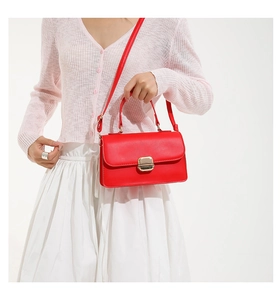 Close-up of red leather handbag with gold metal lock buckle and textured finish