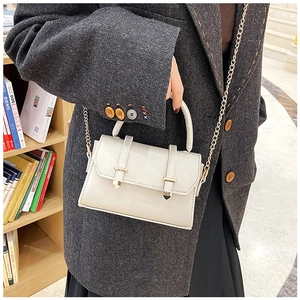 Sac sous le bras beige chic avec chaîne dorée et double sangle dans bibliothèque