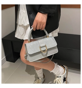 Detail of light gray crossbody bag with sparkling rhinestones and golden D-buckle closure