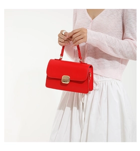 Detail of bright red rectangle handbag featuring premium gold metal clasp and top handle