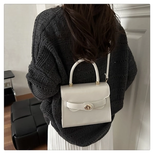 Chic cream leather handbag styled on a textured sweater with gold hardware detail