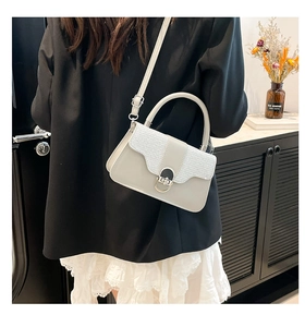 Detail of light gray hardshell bag with wave pattern and metallic clasp on a model