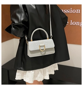Detail of grey crossbody bag featuring sequin patchwork and a large golden D-shaped buckle