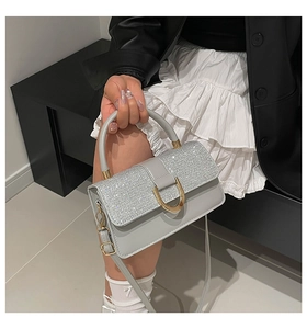 Macro shot of grey leather handbag with sparkling glitter flap and golden horseshoe buckle