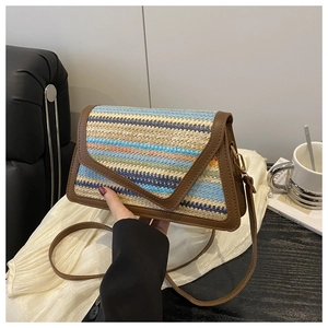 Detail of colorful woven straw shoulder bag with dark brown leather trim and metal clasp