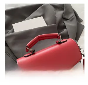 Close-up of the red leather handbag featuring a reinforced round handle and metal buckle