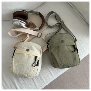 Detail view of nylon crossbody bags in beige and olive green with adjustable straps
