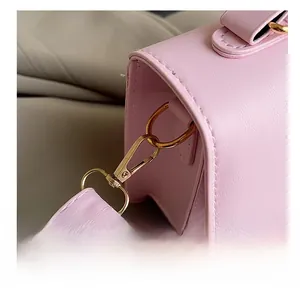 Gros plan du crochet doré et des coutures de précision sur un sac à bandoulière rose