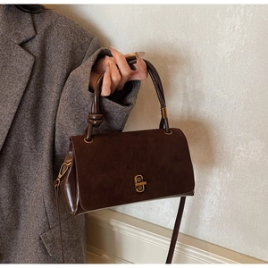 Detail of vintage brown suede crossbody bag with matte gold buckle and knotted handle
