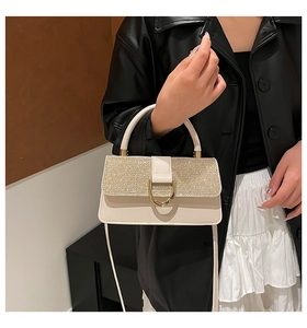 Detail of elegant cream handbag with champagne glitter flap and gold D-shaped buckle