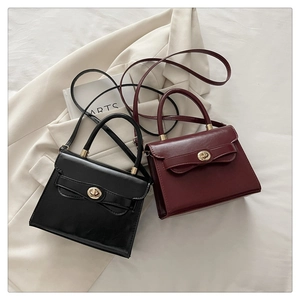 Detail view of glossy leather handbags in black and burgundy with golden twist locks