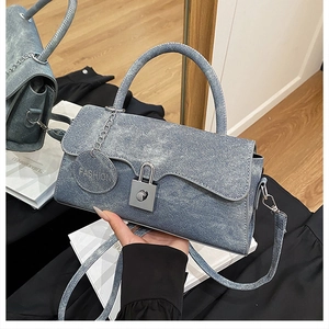 Detail der hellblauen Denim-Umhängetasche mit silbernen Beschlägen und Modeanhänger