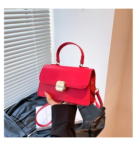 Detail of red leather handbag featuring a signature gold square buckle and top handle